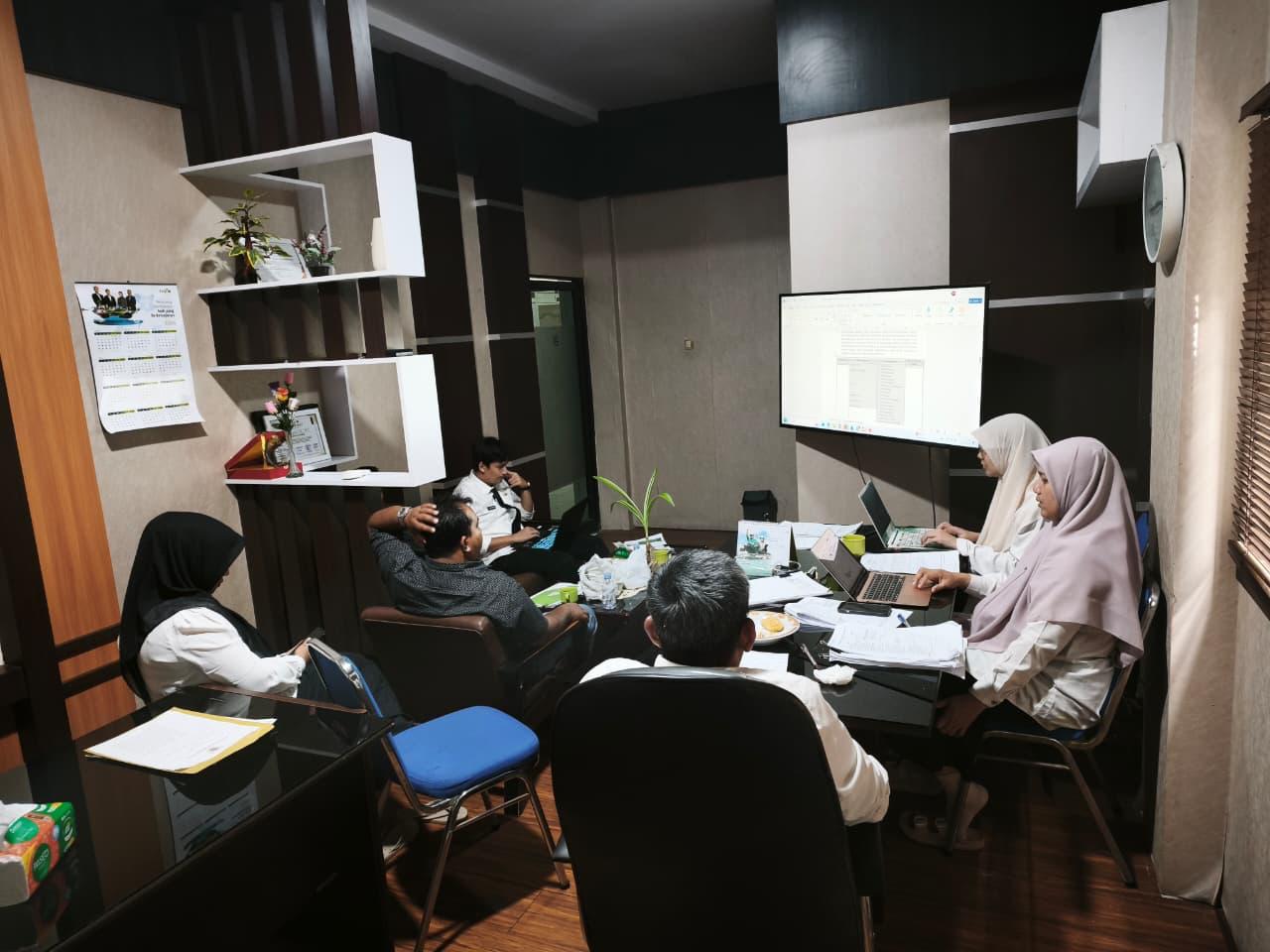 Peserta rapat menelaah dokumen bersama di ruang kerja